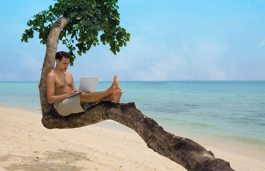 man on laptop at beach
