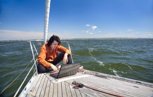 man writing e-newsletters on laptop on boat