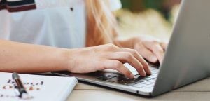 writer practising persuasive writing on computer with notebook