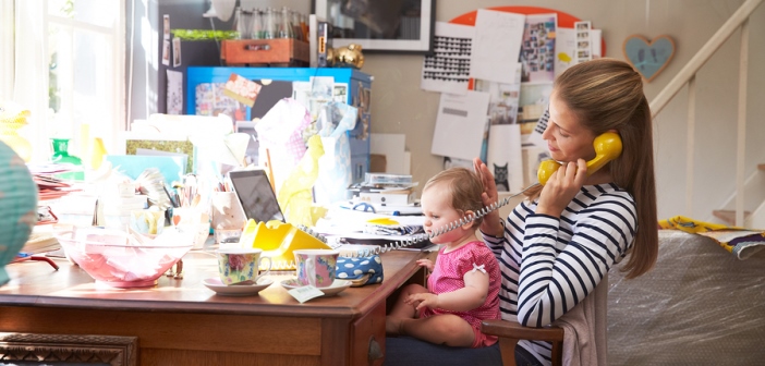 Mother with her kid by computer figuring out payroll