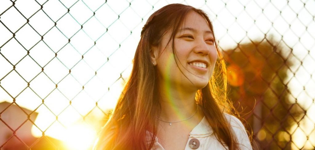 Woman smiling by fence thinking of writing dream