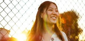 Woman smiling by fence thinking of writing dream