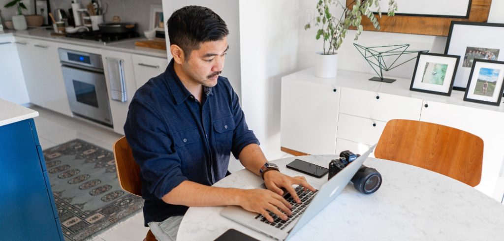 man working on laptop with camera on table