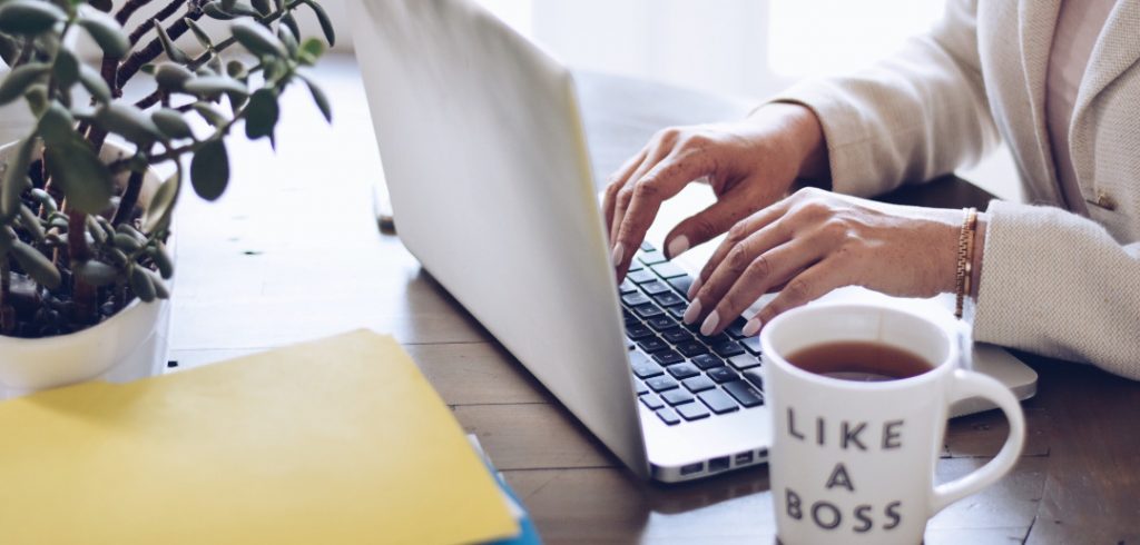 woman with coffee mug next to laptop