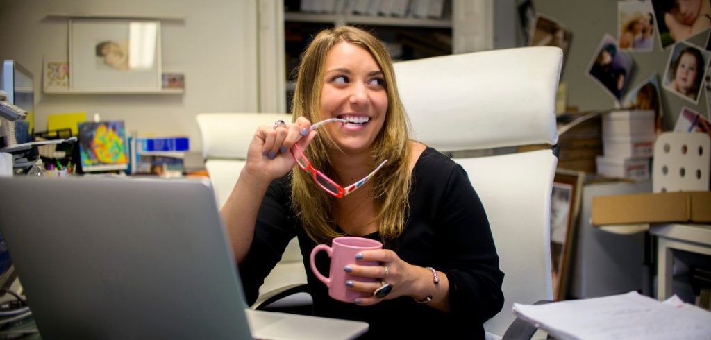 woman by computer smiling finding a profitable writing niche