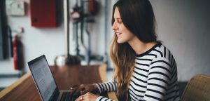 Woman smiling writing compelling copy on laptop