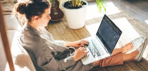 woman writing first draft on laptop in living room