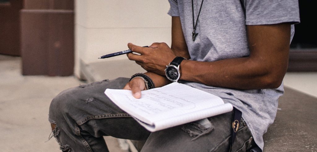 man writing in his authentic voice on a paper pad