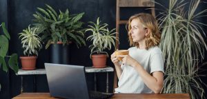 writer with cup practicing mindfulness next to laptop